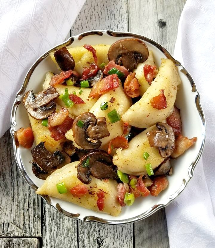 perogies with bacon and mushrooms in a white bowl