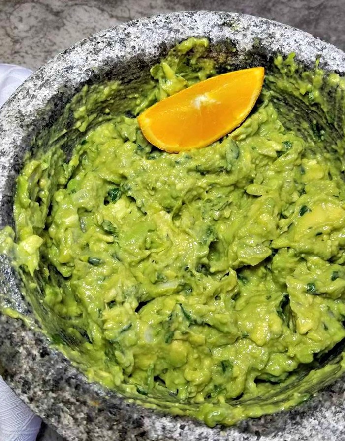 Best Homemade Guacamole in pestle with an orange slice