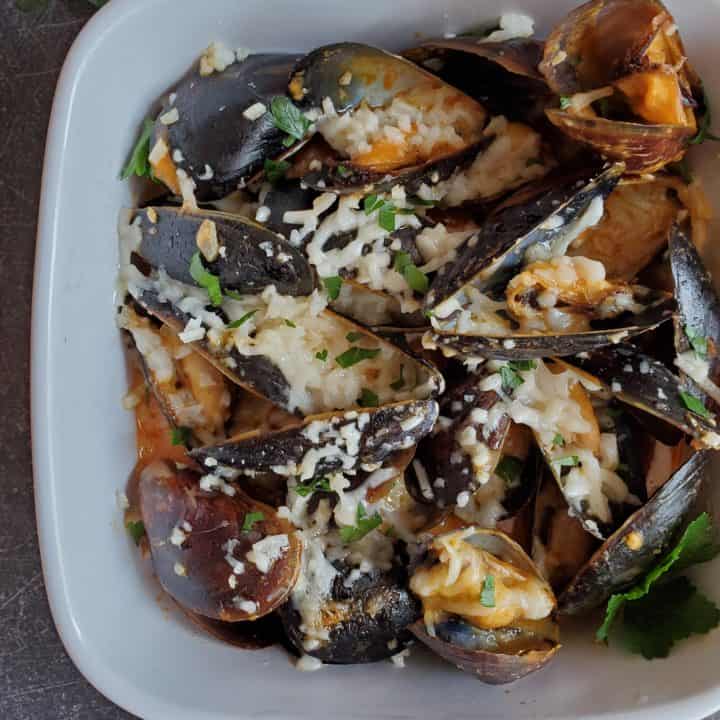 These Mussels are Baked in a Creamy tomato sauce that is topped with mozzarella cheese.